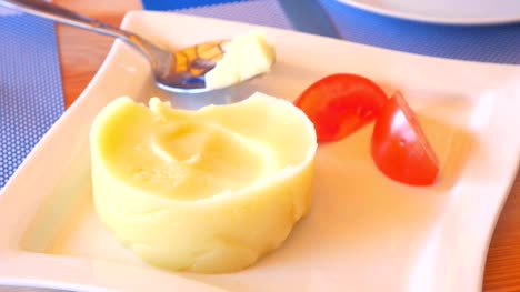 A-woman-spoon-dials-mashed-potatoes-with-tomatoes.-It's-not-tasty.