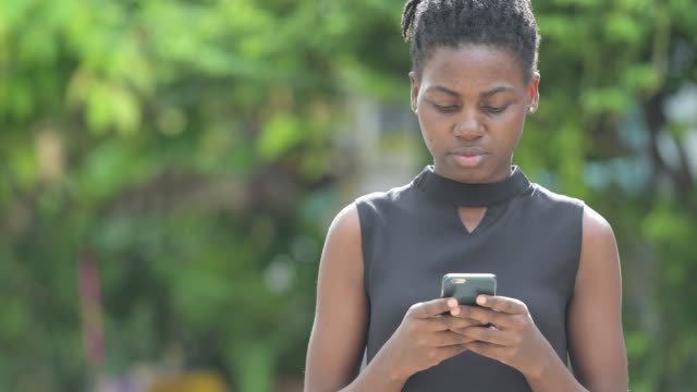 Joven-empresaria-africana-hermosa-con-teléfono-al-aire-libre