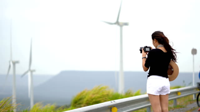 Asiatische-Frauen-Touristen-nehmen-ein-Bild-von-einer-Windkraftanlage-in-eine-landschaftlich-reizvolle-Ort.