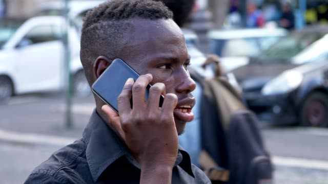 Americano-africano-joven-hablando-por-teléfono-en-el-street-perfil