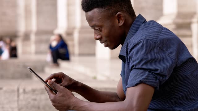 Smiling-American-african-young-man-using-tablet--outdoor