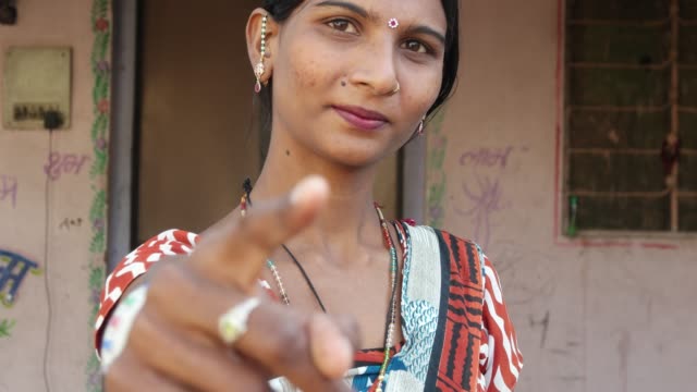 Close-up-of-beautiful-Indian-lady-in-traditional-dress-looks-and-points-at-camera-thumbs-up-best-of-luck-be-good-finger-leader-command-select-face-approves-hand-gesture-smiles-happy-focus-shift