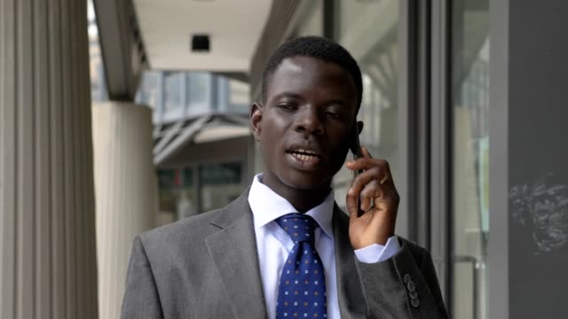 Sicher-schön-schwarzen-amerikanischen-Geschäftsmann-sprechende-Telefon-zu-Fuß-outdoor