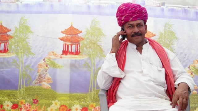 MS-indischer-Mann-sitzen-und-Reden-am-Telefon-mit-traditioneller-Kleidung