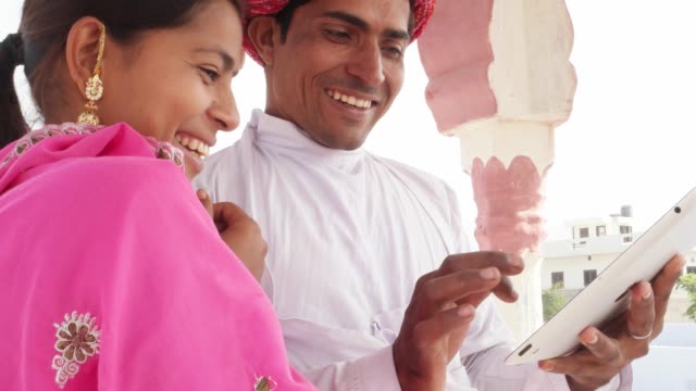 Traditionelle-indische-Braut-mit-rosa-Sari-Multi-farbige-Armbänder-auf-ein-Pad-Ehemann-in-Rajasthan,-Indien