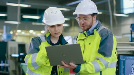 Im-Inneren-der-Herstellungsfabrik-arbeitet-männlichen-Maschinenbauingenieur-auf-PC-unter-Leitung-von-Frau-Chief-Project-Engineer.