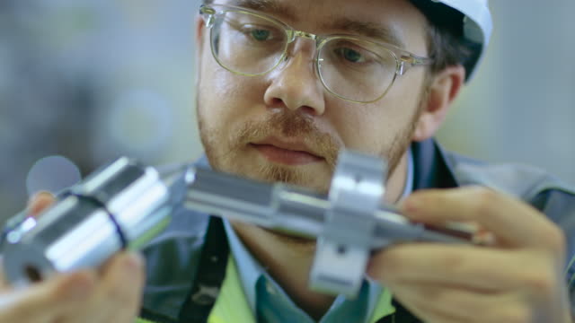 Close-up-Shot-of-the-Industrial-Engineer-Wearing-Classes-and-Hard-Hat-Connects-Two-Components-He-Designed.-Precision-in-Mechanical-Engineering.