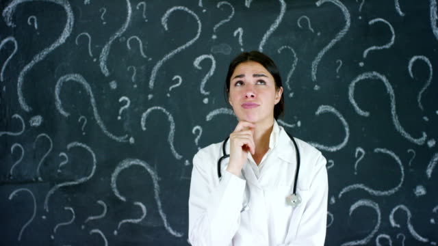 Portrait-of-a-beautiful-female-doctor-(student)-thinking-about-choosing-a-profession,-at-a-black-board.
