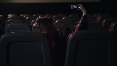 Junge-Menschen-küssen-im-leeren-Kinosaal.-Liebe-paar-machen-Selfie-Foto