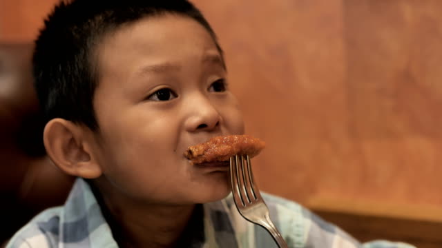 Lindo-muchacho-asiático-son-felices-comiendo-pollo-asado-en-el-restaurante.-Video-4k-lenta