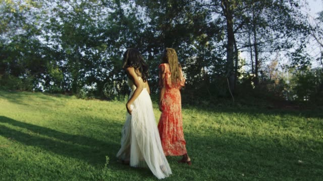 Lenta-de-dos-mujeres-llevando-vestidos-y-caminando-en-un-hermoso-parque