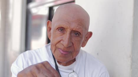 Ein-Alter-spanischer-Mann-starrt-in-die-Kamera-beim-Sitzen-auf-der-Straße-in-Mexiko