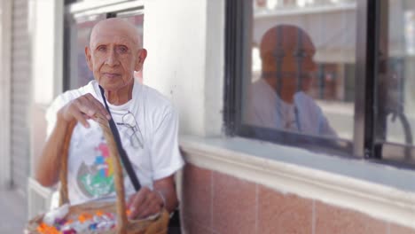 Hispana-viejo-hombre-mira-fijamente-a-la-cámara-mientras-sostiene-una-cesta-de-dulces-se-vende-en-las-calles-de-México