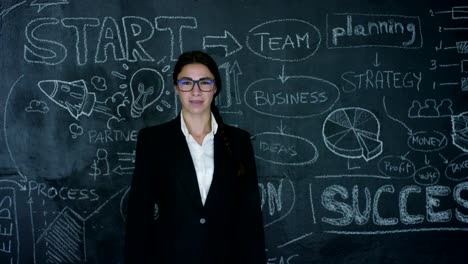 Beautiful-business-girl,-marketing-teacher,-draws-a-graph-of-success-on-a-black-board,-on-a-black-background.