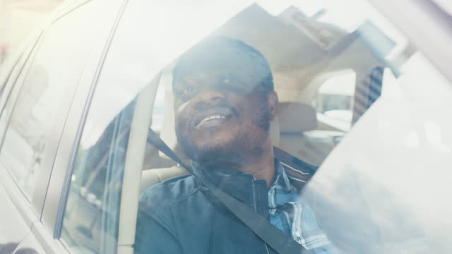 Handsome-Young-Black-Man-Rides-on-a-Passenger-Seat-of-a-Car,-Looks-out-of-the-Window.-Big-City-View-Reflected-in-Window.-Camera-Mounted-outside-Moving-Car.