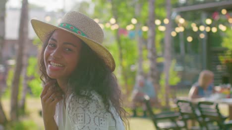 Portrait-of-Beautiful-Black-Girl-in-a-Hat-Charmingly-Smiling,-Touching-Her-Hair.-Attractive-Girl-on-a-Summer-Day-Relaxes-in-the-Garden.-In-Slow-Motion.