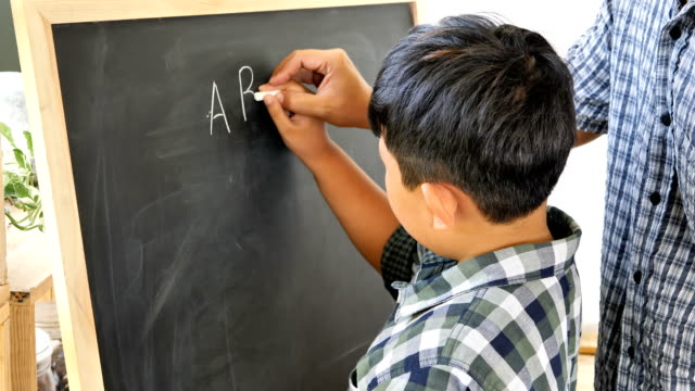 Father-teaches-children-boy-to-writing-the-chalkboard.-Education-concept.