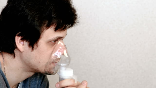 Utilice-el-nebulizador-y-el-inhalador-para-el-tratamiento.-Hombre-joven-inhalando-a-través-de-mascarilla-inhalador.-Vista-lateral.