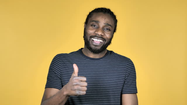 Casual-African-Man-Gesturing-Thumbs-Up-Isolated-on-Yellow-Background