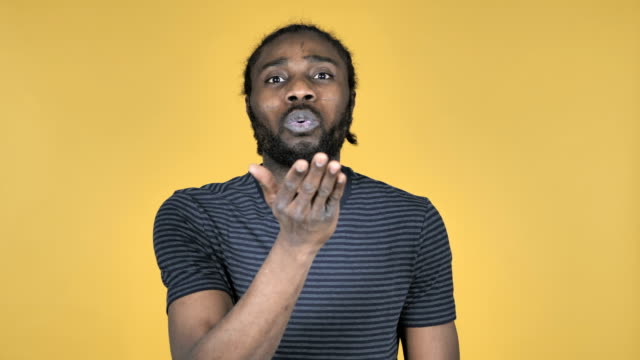 Flying-Kiss-by-Casual-African-Man-Isolated-on-Yellow-Background
