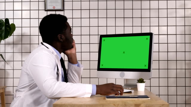 Junge-afrikanische-Ärztin-suchen-auf-Monitor-seines-Computers.-Weißes-Display
