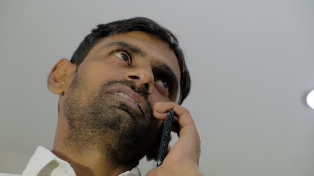 Looking-up-static-shot-of-a-man-with-stubble-talking-on-a-smart-phone-device