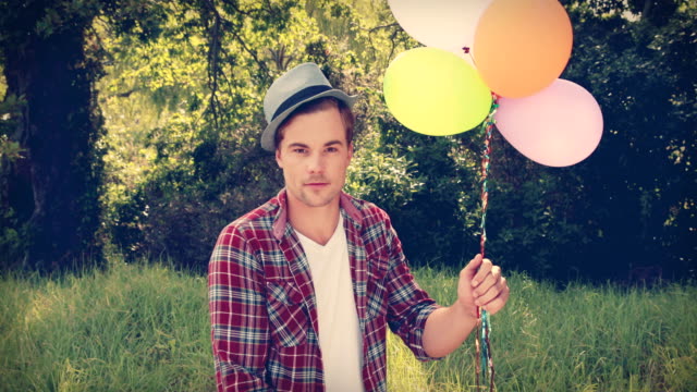 Handsome-hipster-holding-balloons
