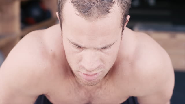 A-fit-young-man-with-water-dripping-off-of-him-after-a-workout-looks-up-at-the-camera
