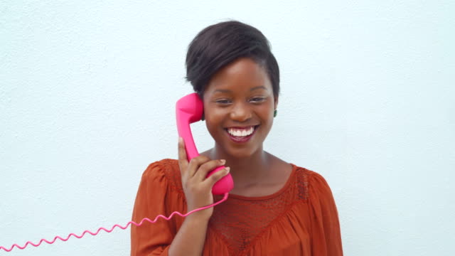 Smiling-happy-young-woman-talking-on-the-pink-telephone