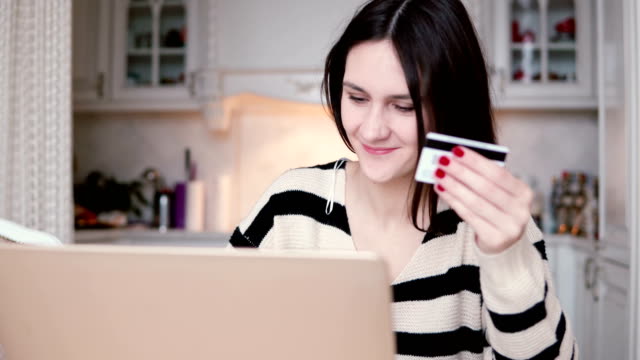 Atractiva-joven-sonriente-utiliza-plástico-tarjeta-de-crédito-de-compras-online-con-el-ordenador-portátil.-control-deslizante-a-la-derecha