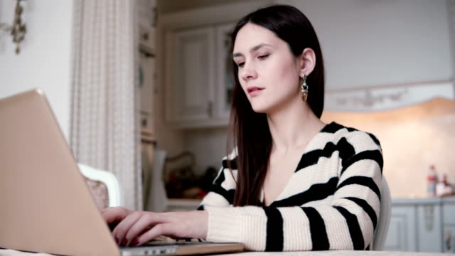 Porträt-einer-schönen-junge-Brünette-Frau-nutzt-Laptop-in-ein-helles-Esszimmer