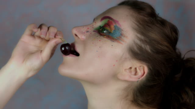 4k-Shot-of-a-Woman-with-Multicoloured-Make-up-Eating-Cherry