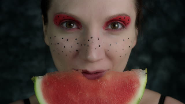 4-k-Aufnahme-einer-Frau-mit-bunten-Make-up-eine-Wassermelone-essen