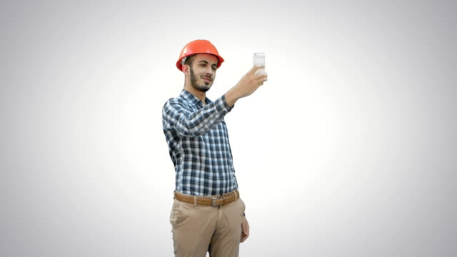 Trabajador-de-la-construcción-usando-el-teléfono-para-tomar-selfies-sobre-fondo-blanco