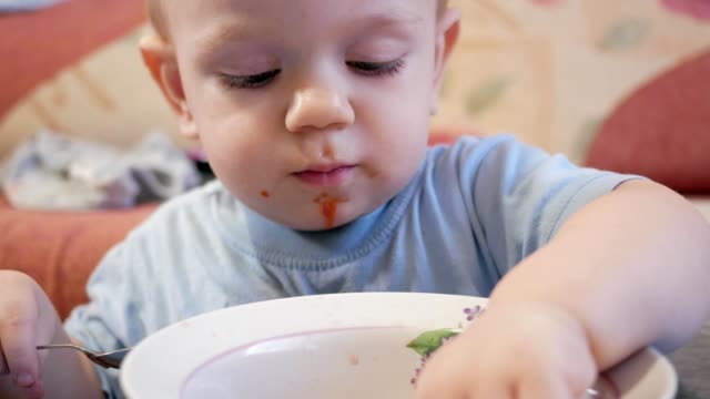 Eine-attraktive-junge-2-Jahre-alt-ist,-rote-Suppe-selbst-essen.-Das-Lorbeerblatt-gefangen-in-einem-Teller-und-das-Kind-spielt-mit-ihm