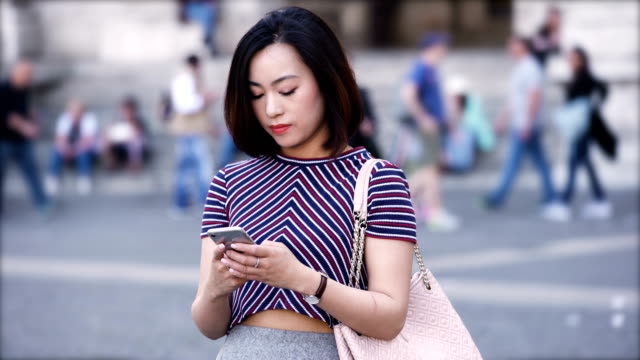 Portrait-of-a-young,-attractive-chinese-woman-using-smartphone-in-the-city