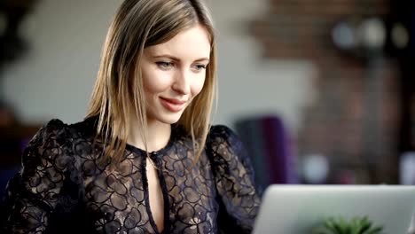 Beautiful-woman-with-long-blond-hair-picks-a-present-for-her-girlfriend-using-the-internet-on-her-laptop,-she-looks-at-the-monitor-with-a-smile