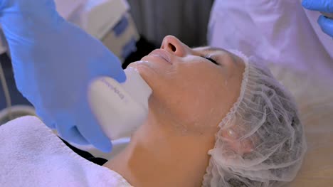 Cosmetologist-cleans-a-woman's-face-with-electronic-equipment