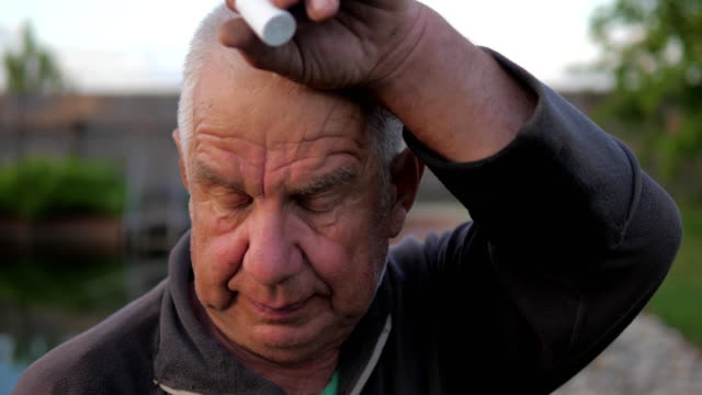 Portrait-of-an-elderly-man,-wiping-his-hand-with-sweat-from-his-forehead.