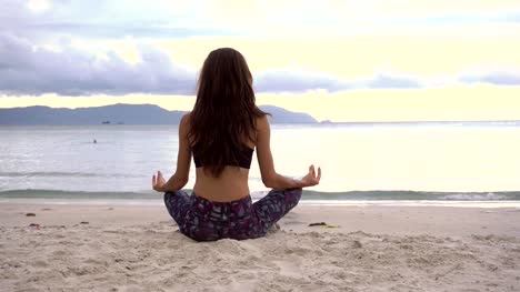 Yoga-meditating-in-lotus-pose-on-beach.