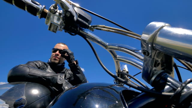 Biker,-Motorradfahrer-Pausen-Hände-auf-einen-Helm-und-berührt-seine-Sonnenbrille.-4K.