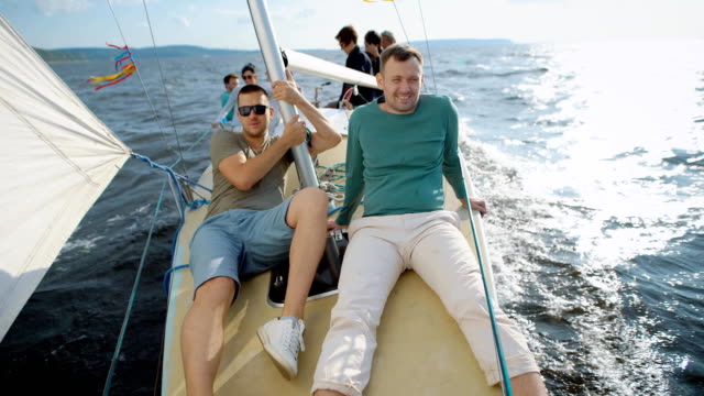 Men-sitting-on-modern-yacht-posing-and-smiling-at-camera