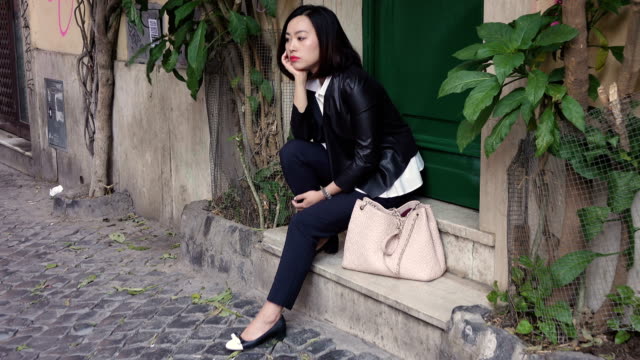 pensive-sad-beautiful-asian-woman-sitting-in-a-little-street-steady-cam