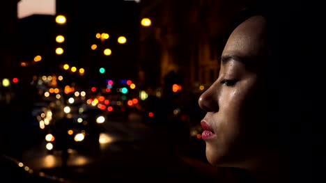 Sad,-depressed-Chinese-young-woman's-profile-cries,-night-city-in-background