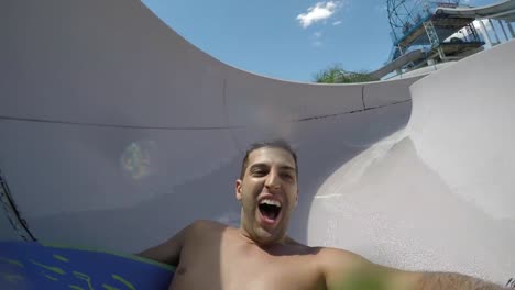 Man-having-fun-and-sliding-down-in-a-water-slide