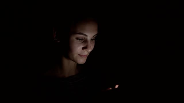Nahaufnahme-einer-Frau-mit-ihrem-Handy-in-einem-dunklen-Raum-in-der-Dunkelheit-mit-Smartphone,-chatten-mit-Freunden-online-zu-kommunizieren