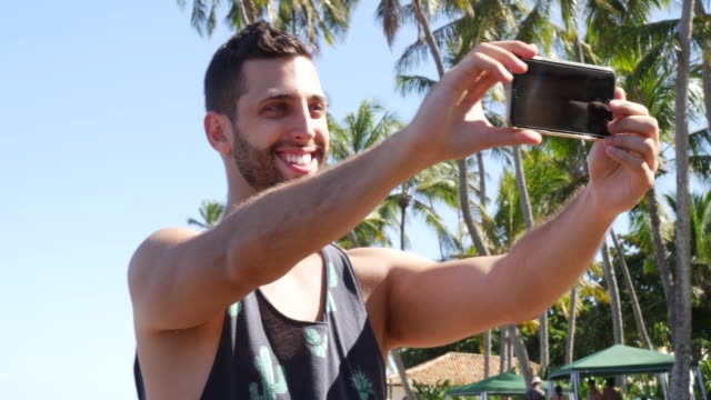 Young-Man-taking-a-selfie-in-Forte-Beach,-Brazil