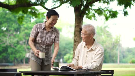 Asian-senior-retire-couple-drink-coffee-and-read-book-in-park