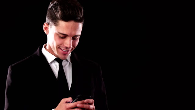 A-smiling-guy-in-a-suit-is-typing-something-in-his-phone