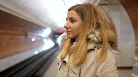 Attraktive-Frau-stehen-in-der-u-Bahn-und-mit-dem-Smartphone-einen-Zug-wartet.